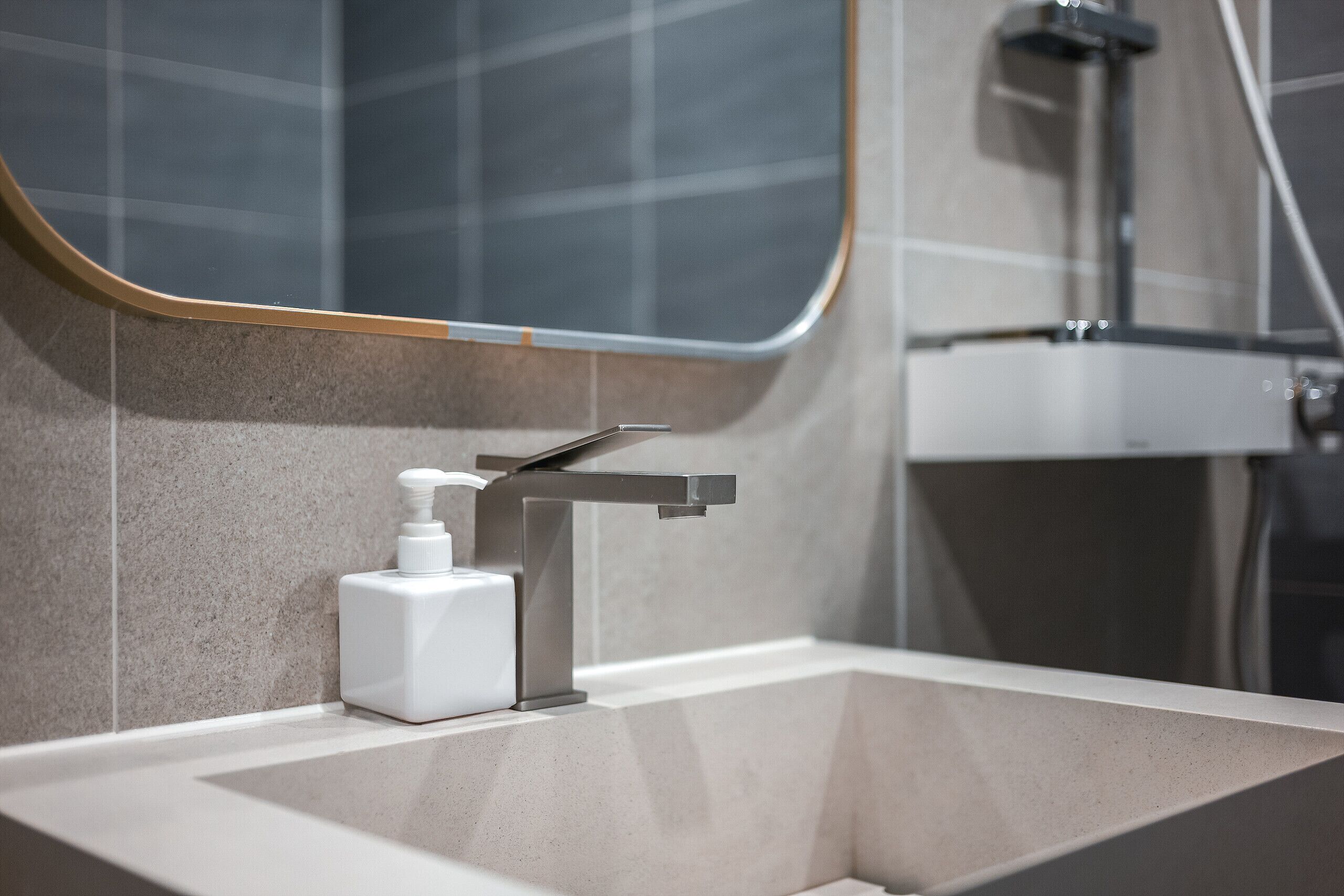 A bathroom with a modern sink, a mirror, and a shower.
