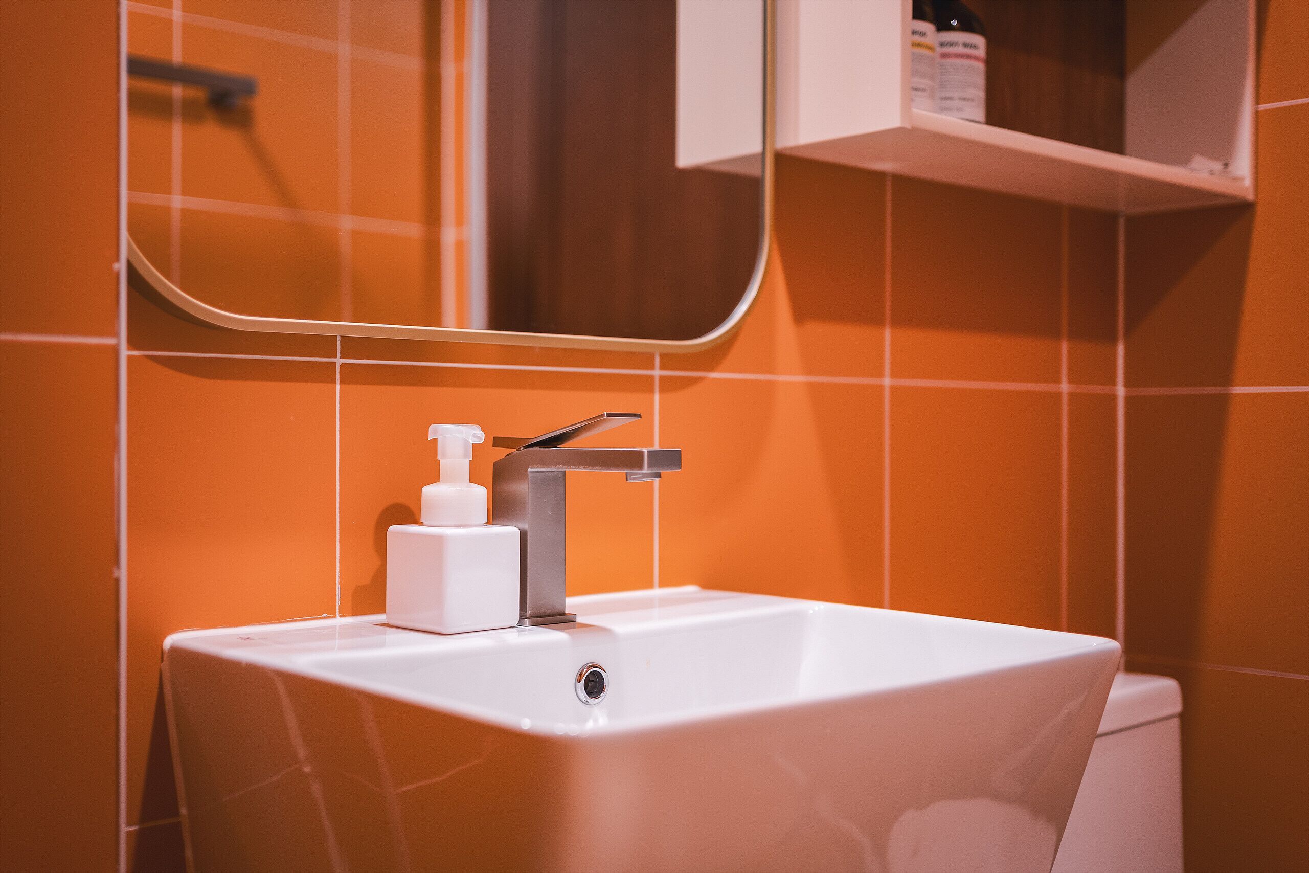 Un baño con un lavamanos blanco, un grifo plateado y un dispensador de jabón blanco.