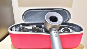 Un estuche rojo de viaje con un objeto metálico en su interior, posiblemente un dispositivo portátil.