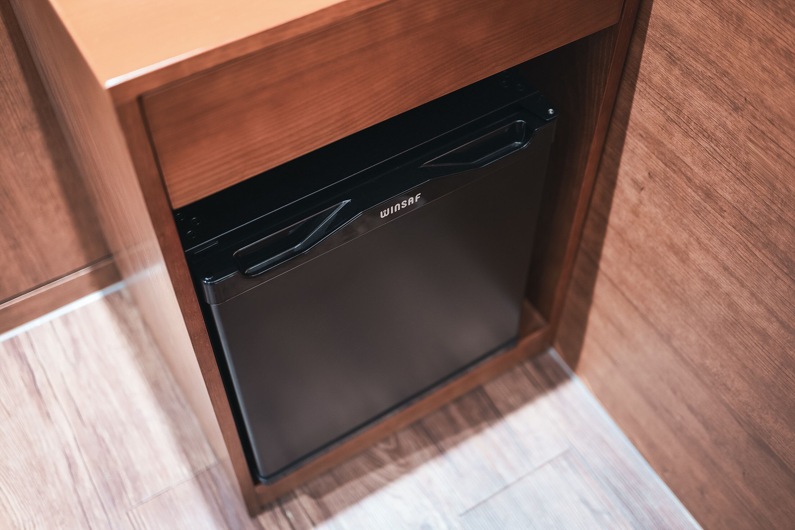 A black dishwasher installed in a wooden cabinet with a handle.