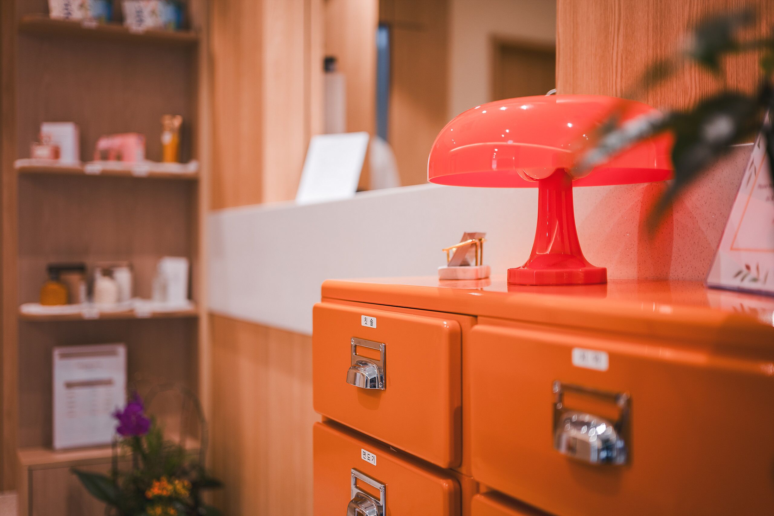 A room with wooden shelving, a red lamp, and orange filing cabinets.