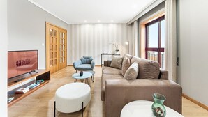 Een moderne woonkamer met een televisie, bank, fauteuil en een klein tafeltje.