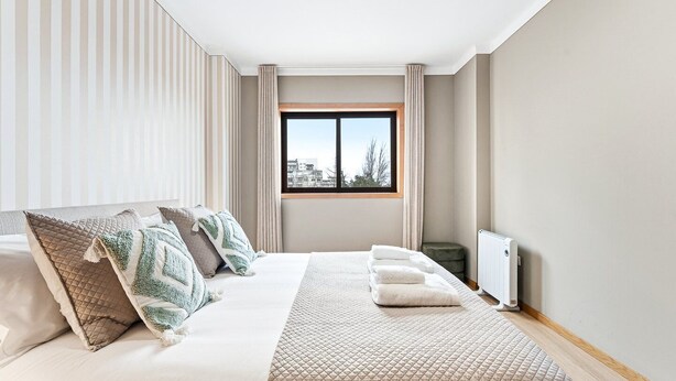 Een moderne hotelkamer met een groot bed, een raam met uitzicht op de stad en een radiator.