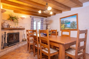 Ein Essbereich mit Holztisch und -stühlen, einem Kamin und einem Gemälde an der Wand.