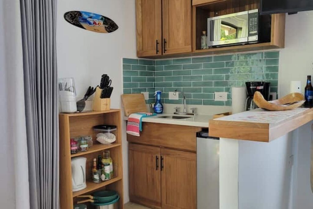 Una cocina compacta con armarios de madera, un microondas y un lavamanos.