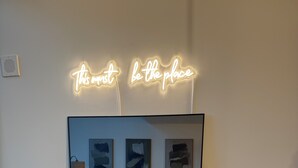 Un salón moderno con un espejo grande que refleja un sofá, cojines y arte abstracto en la pared.