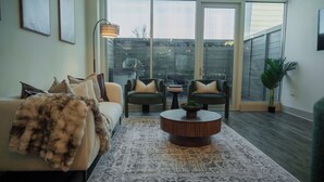 Una sala de estar moderna con un sofá, dos sillones, una mesa de centro y un amplio ventanal con vista a una terraza.
