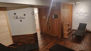 A room with a wooden door, a relaxation area with a chair and a bench, and a wall with a clock and the words "Relax". - Suite by the forest (Bad Sachsa)