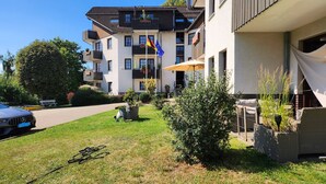 A modern multi-story residential building with balconies, a flag, and a garden area. - Suite by the forest (Bad Sachsa)