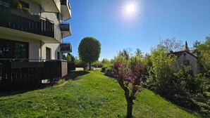 A residential area with a modern apartment building, a well-maintained lawn, and a tree with pink blossoms. - Suite by the forest (Bad Sachsa)