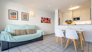 Ein modernes Wohnzimmer mit einer Couch, einem Esstisch mit Stühlen und einer Küchenzeile inklusive Mikrowelle.