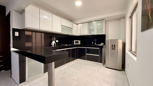 A modern kitchen with a black countertop, white cabinets, and a built-in microwave.