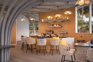 A bar area with wicker chairs, a bar counter with bottles, and pendant lighting. - Praveg Atolls Thinnakara Lakshadweep (Tinnikara)
