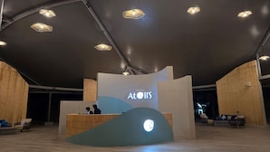 Un espace d’accueil au design moderne, avec un comptoir d’accueil aux lignes courbes et un logo affiché sur le mur.