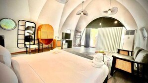 Une chambre d’hôtel moderne dotée d’un grand lit, d’un coin salon avec une table ronde et d’une vue sur un balcon.