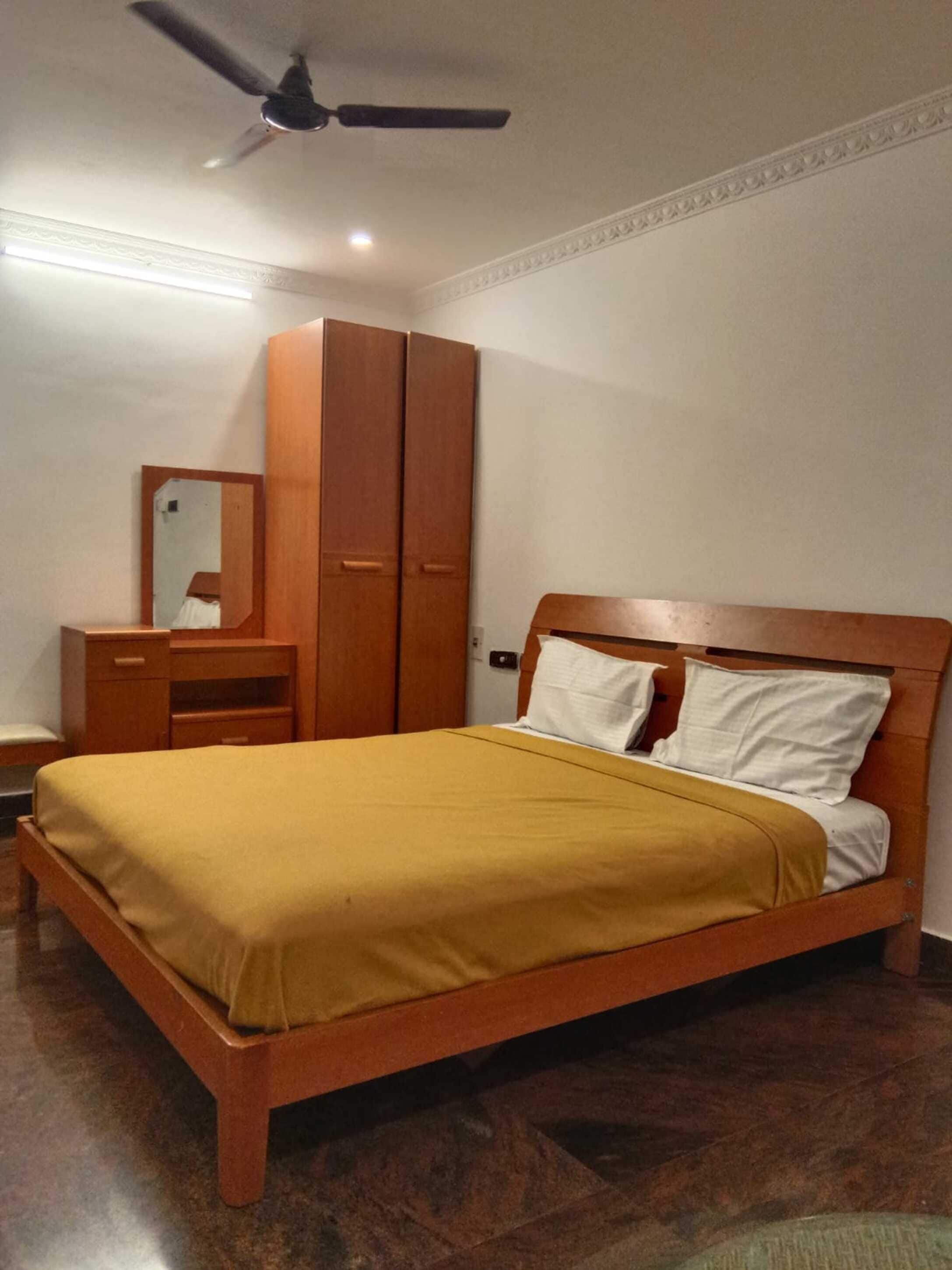 Una camera da letto con un letto in legno, un armadio, uno specchio e una ventola a soffitto.