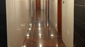 A long, well-lit hallway with a shiny floor, leading to a door at the end. - Hotel Grand International (Erode)
