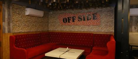 A red upholstered booth with a white table in the center, a brick wall, and a sign that reads "OFFSIDE".