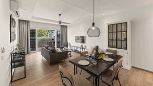 Una sala de estar moderna con comedor, televisor y balcón con cortinas.