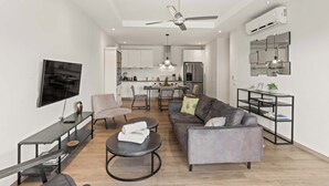 Una sala de estar moderna con un sofá, una mesa de centro, televisor y un comedor con sillas y una mesa.