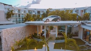 A modern hotel with a central courtyard, outdoor seating, and a covered area with a car parked on top. - BPH04 CPL, Luxury estudio PH con piscina privada (Tulum)