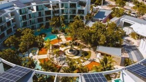 A modern hotel with a circular pool surrounded by lush greenery and solar panels on the roof. - B205 CPL, Amazing air conditioned studio (Tulum)