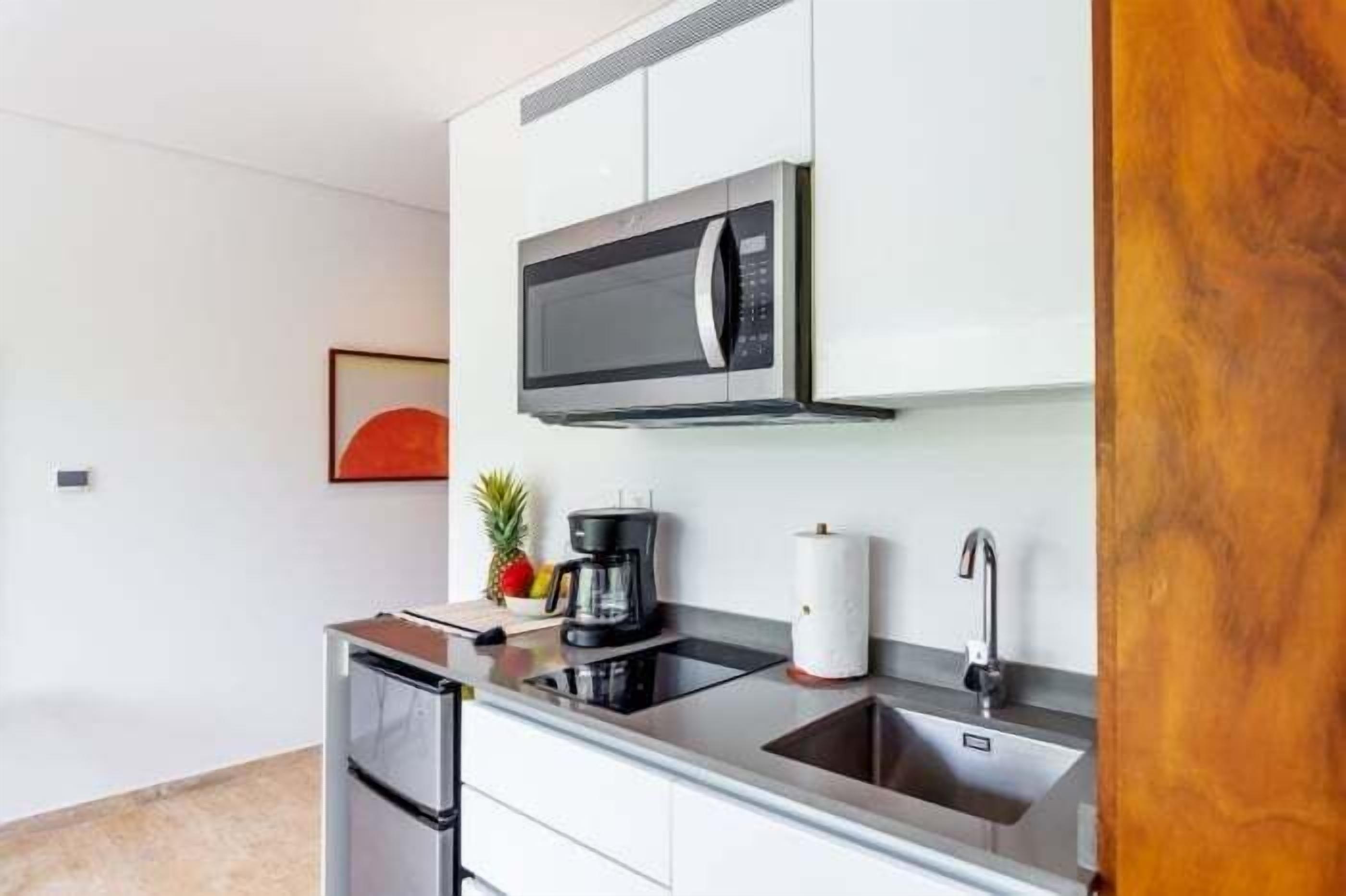 A modern kitchen with a built-in microwave, a coffee maker, and a sink.