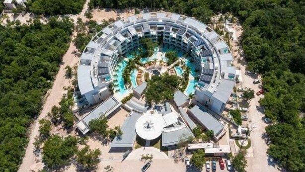 Um hotel circular com piscina central, rodeado por quartos de hóspedes e comodidades.