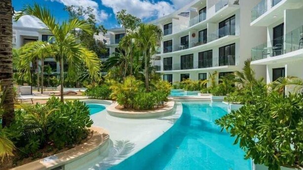 Un hôtel moderne doté d’une piscine entourée d’une végétation luxuriante et de palmiers.