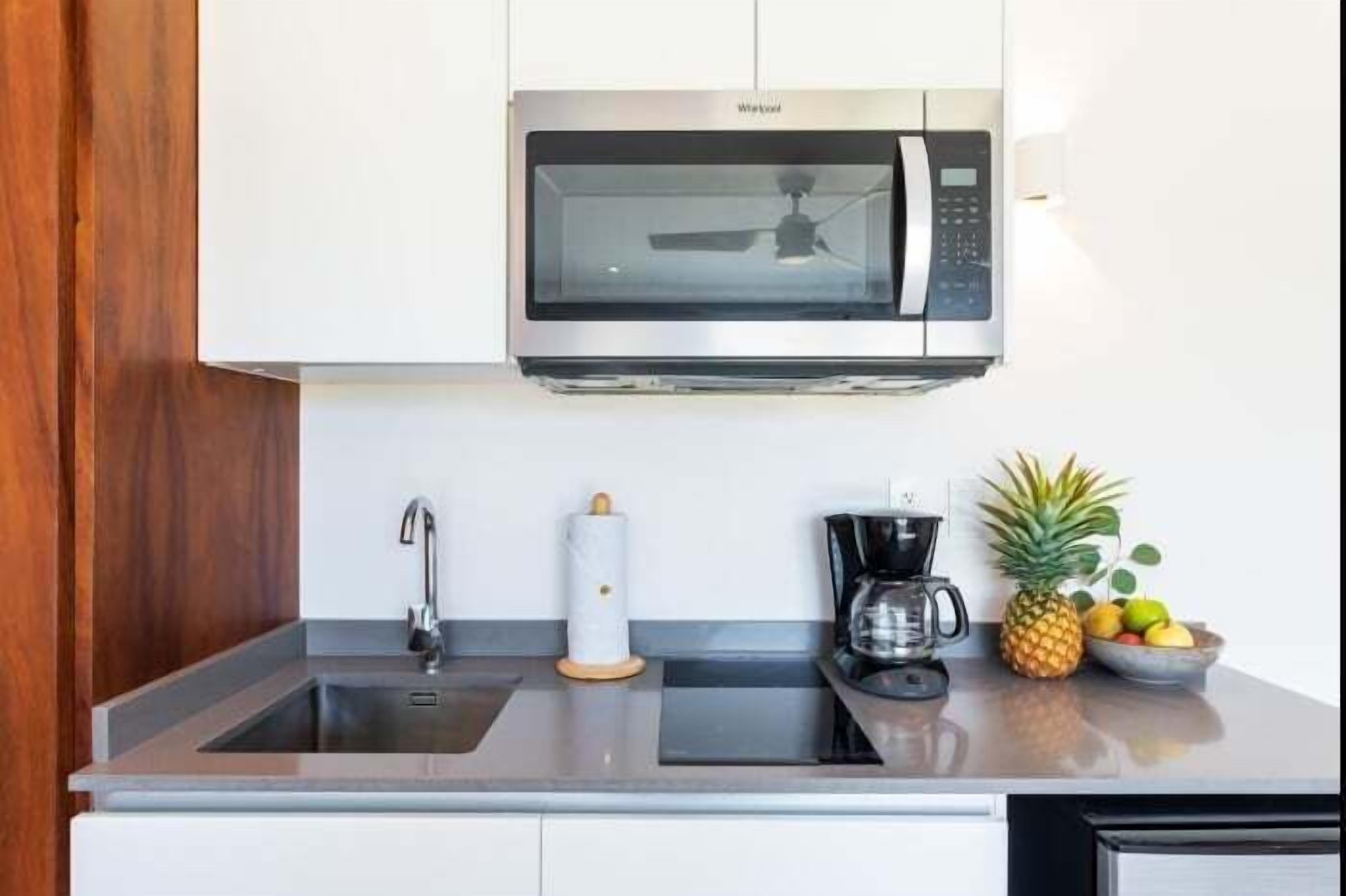 A kitchen with a microwave, sink, and coffee maker.
