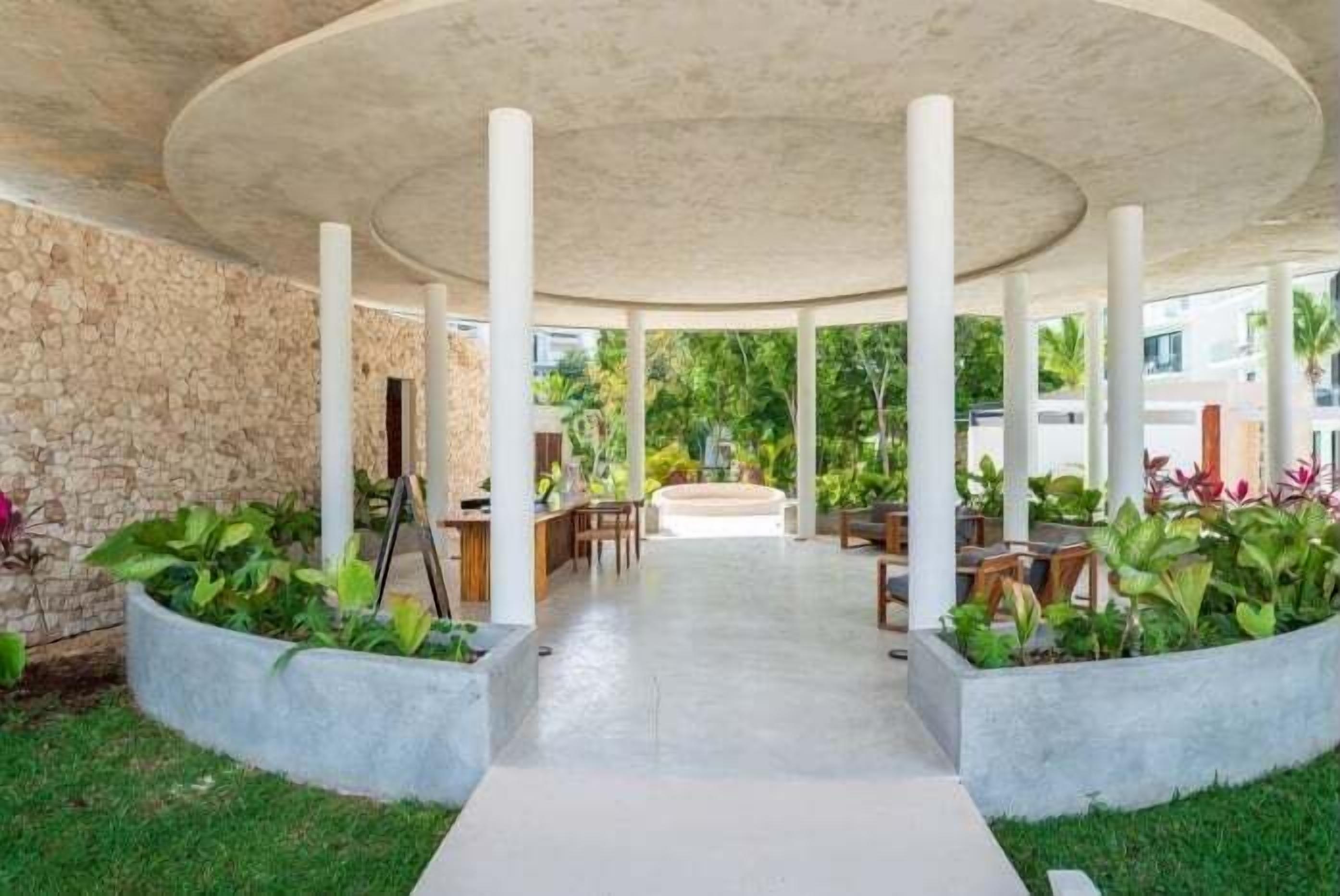 A covered outdoor area with stone walls, a central pathway, and seating arrangements.