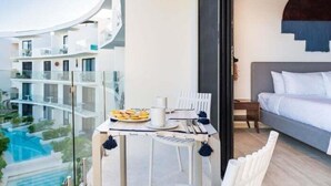 A modern hotel room with a balcony, a bed, and a dining table set with breakfast. - D308 CPL / Alberca / Estilo / Cowork /Relax (Tulum)