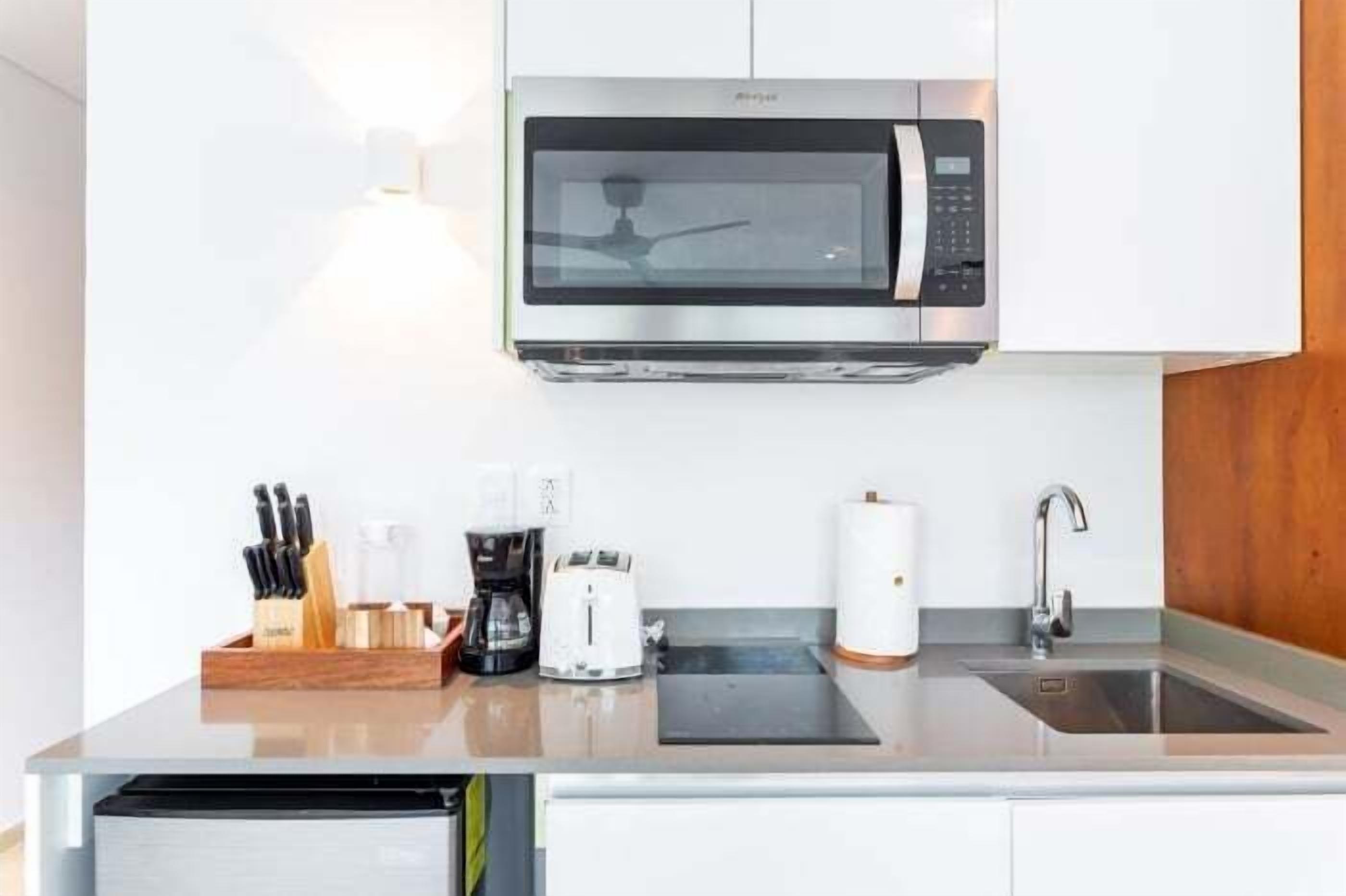 A modern kitchen with a built-in microwave, coffee maker, toaster, and a stainless steel sink.
