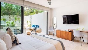Une chambre d’hôtel moderne équipée d’un lit, d’un bureau, d’une télévision et d’un balcon agrémenté de plantes.