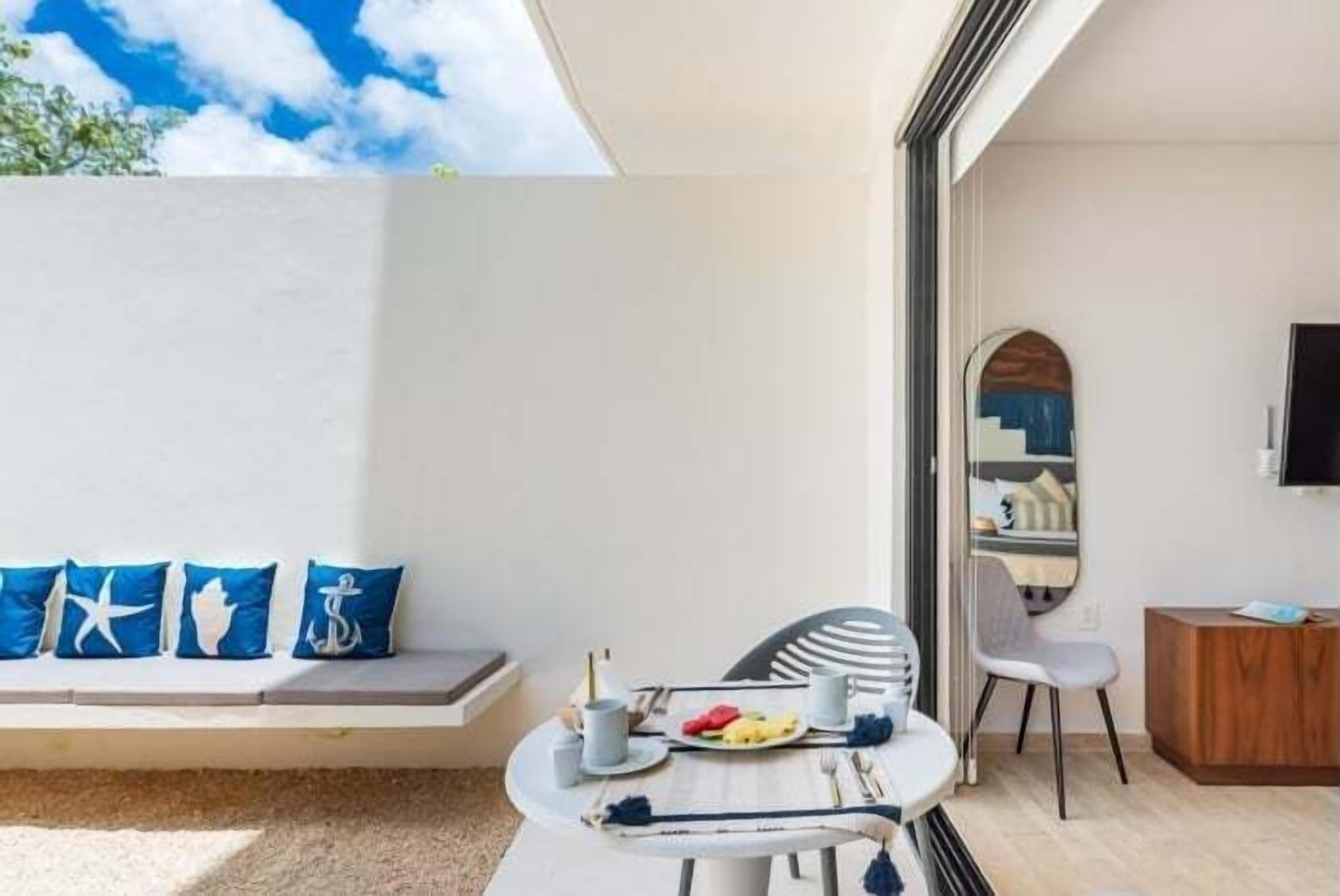 A modern room with a dining area, a sofa with nautical-themed cushions, and a television on the wall.