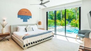 A modern bedroom with a large bed, a ceiling fan, and a view of a swimming pool. - D104 CPL, Grandioso 2 bedrooms swim up (Tulum)