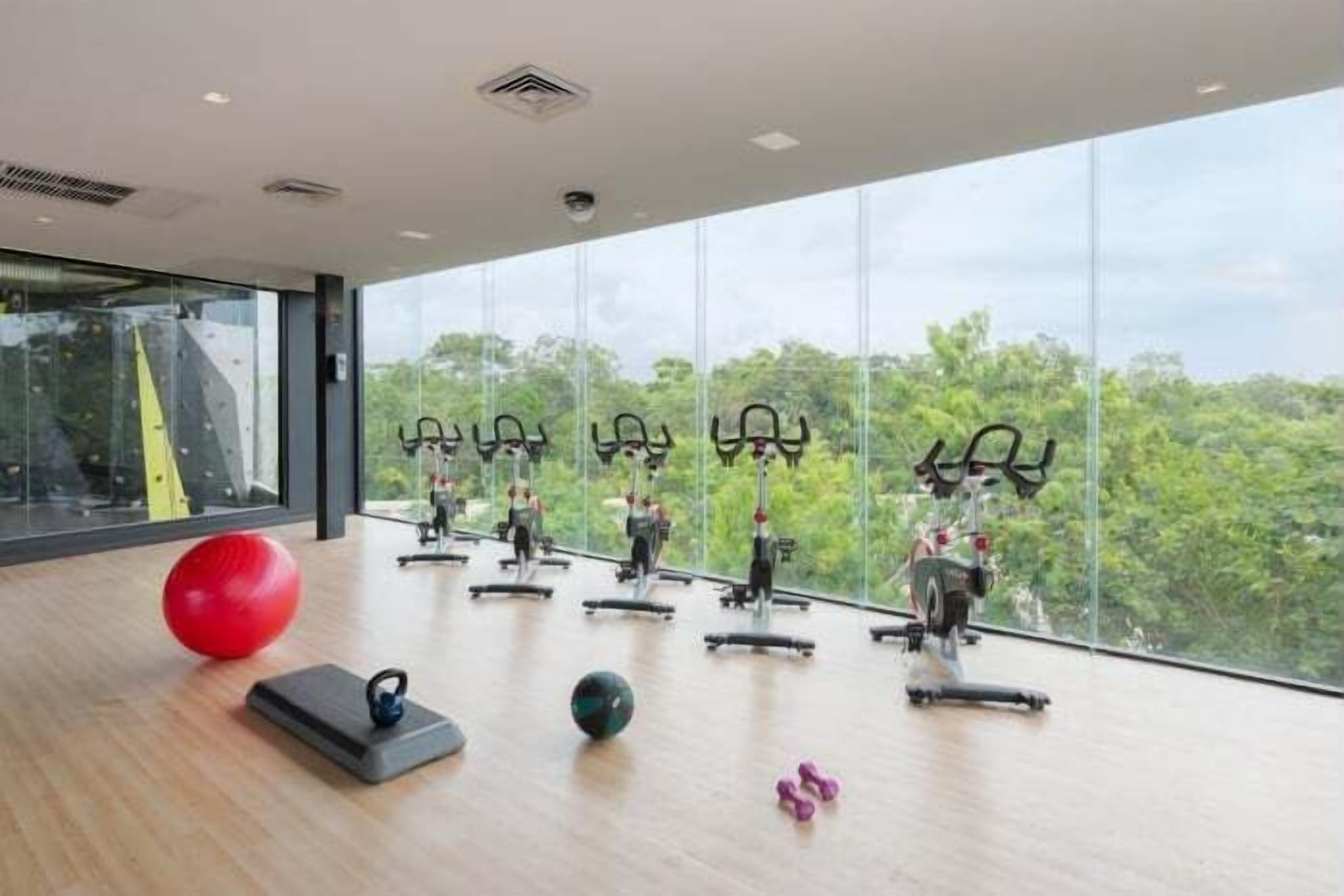 Ein Fitnessraum mit Trainingsgeräten, einem roten Trainingsball und Kurzhanteln.