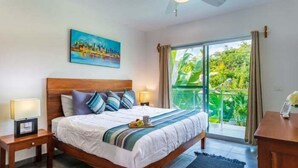 Una camera da letto con un letto grande, un quadro al muro e un balcone con vista sul verde.