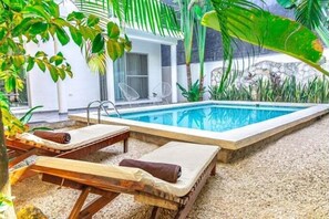 A pool area with lounge chairs and a stone wall. - Casa Alegria, New Villa Private Pool! (Tulum)
