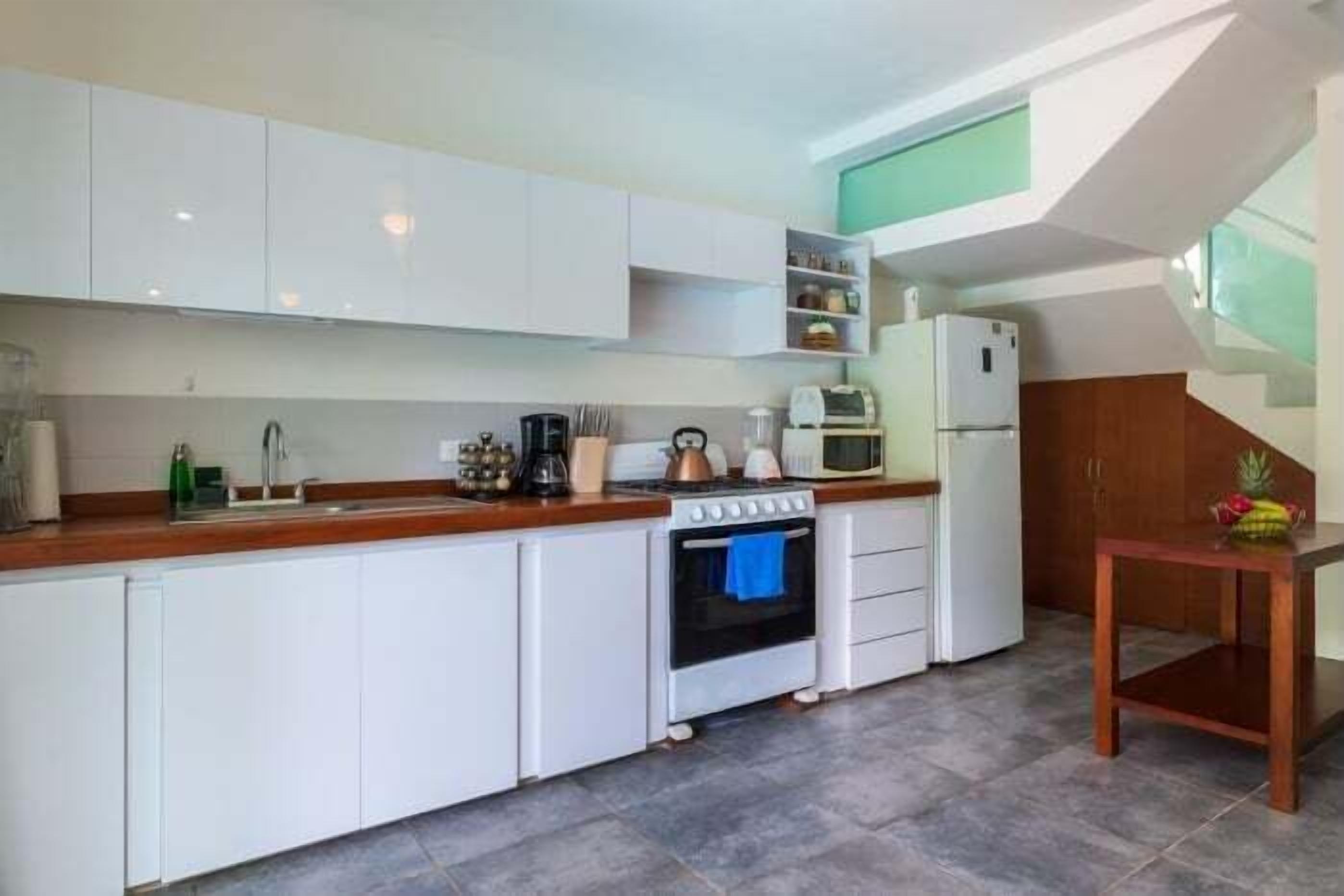 Een moderne keuken met witte kasten, een houten aanrecht, een fornuis en een magnetron.