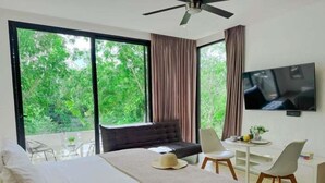 Ein modernes Hotelzimmer mit einem großen Bett, einem Fernseher, einem Schreibtisch und Blick ins Grüne.