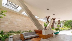 Eine moderne Lobby mit einer Rezeption, einer Sitzecke und einem großen Oberlicht.