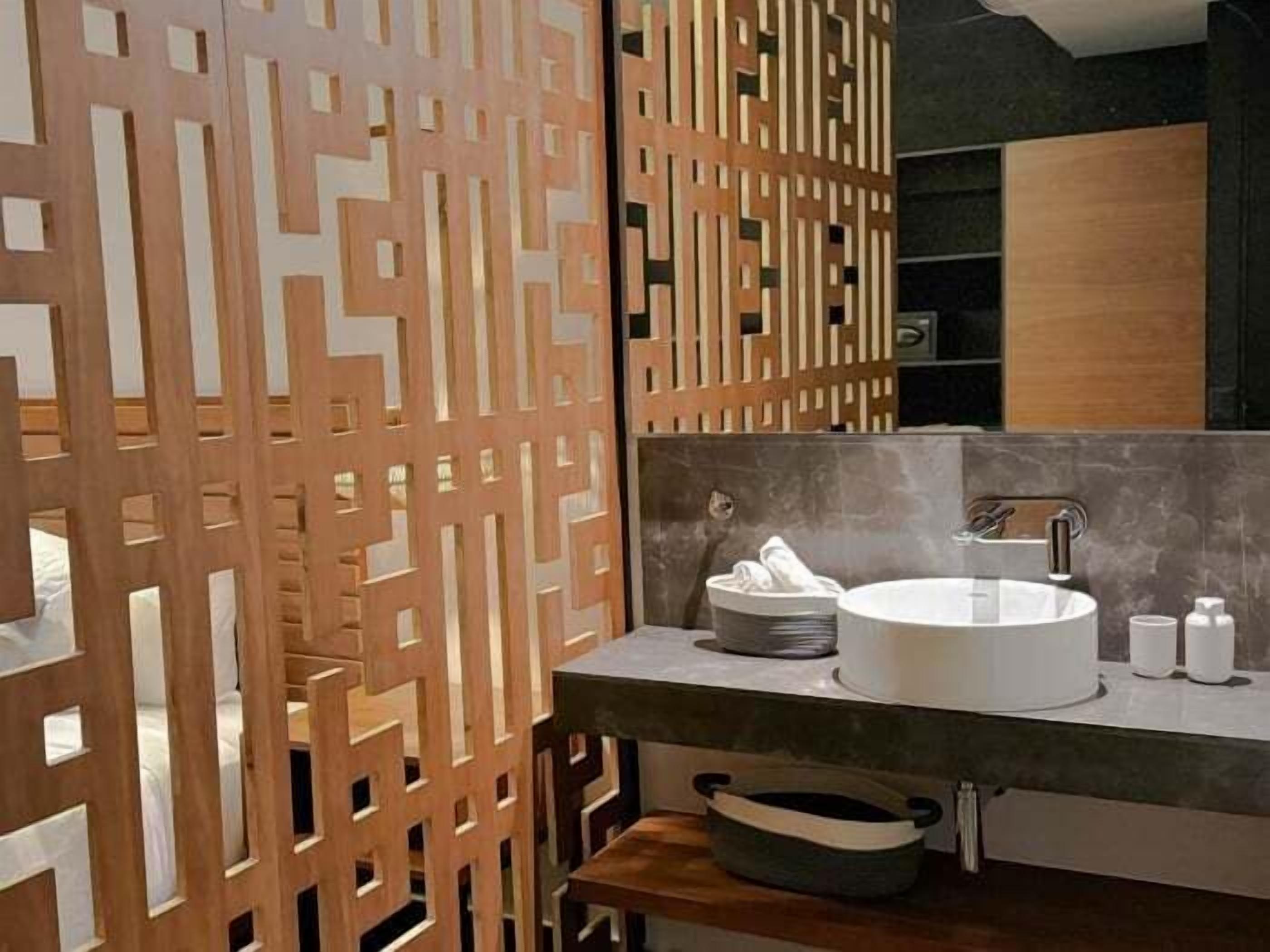 A modern bathroom with a wooden partition, a round sink, and a mirror.