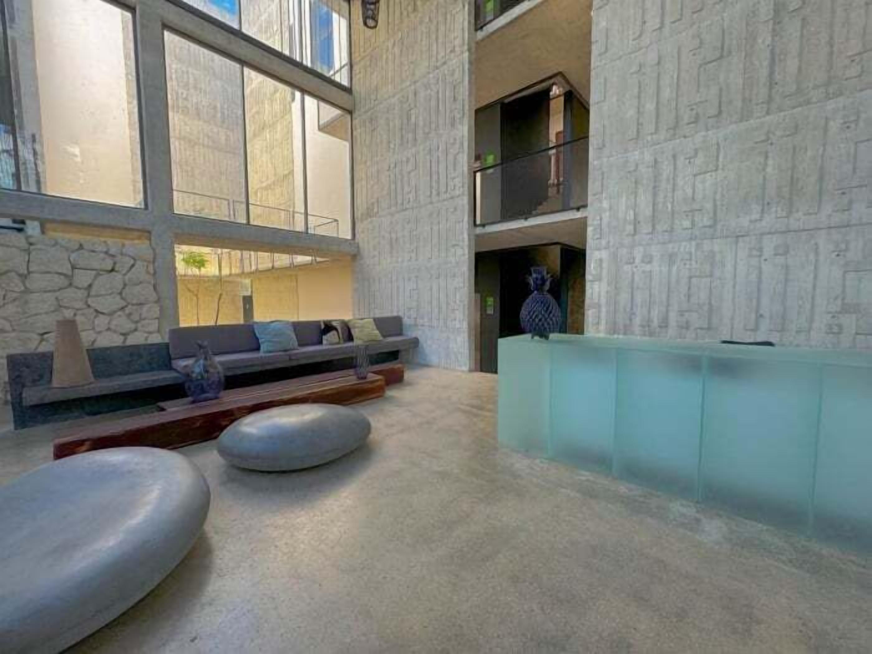 A spacious lobby with a stone wall, a seating area with sofas, and a reception desk.