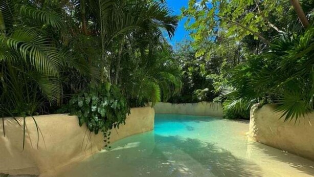 A clear swimming pool surrounded by lush greenery and a sandy deck. - IIK C409, Luxury Studio/private individual pool (Tulum)