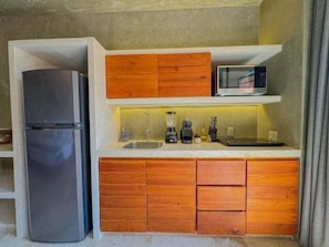 Eine kleine Küche mit Kühlschrank, Mikrowelle und Holzschränken.