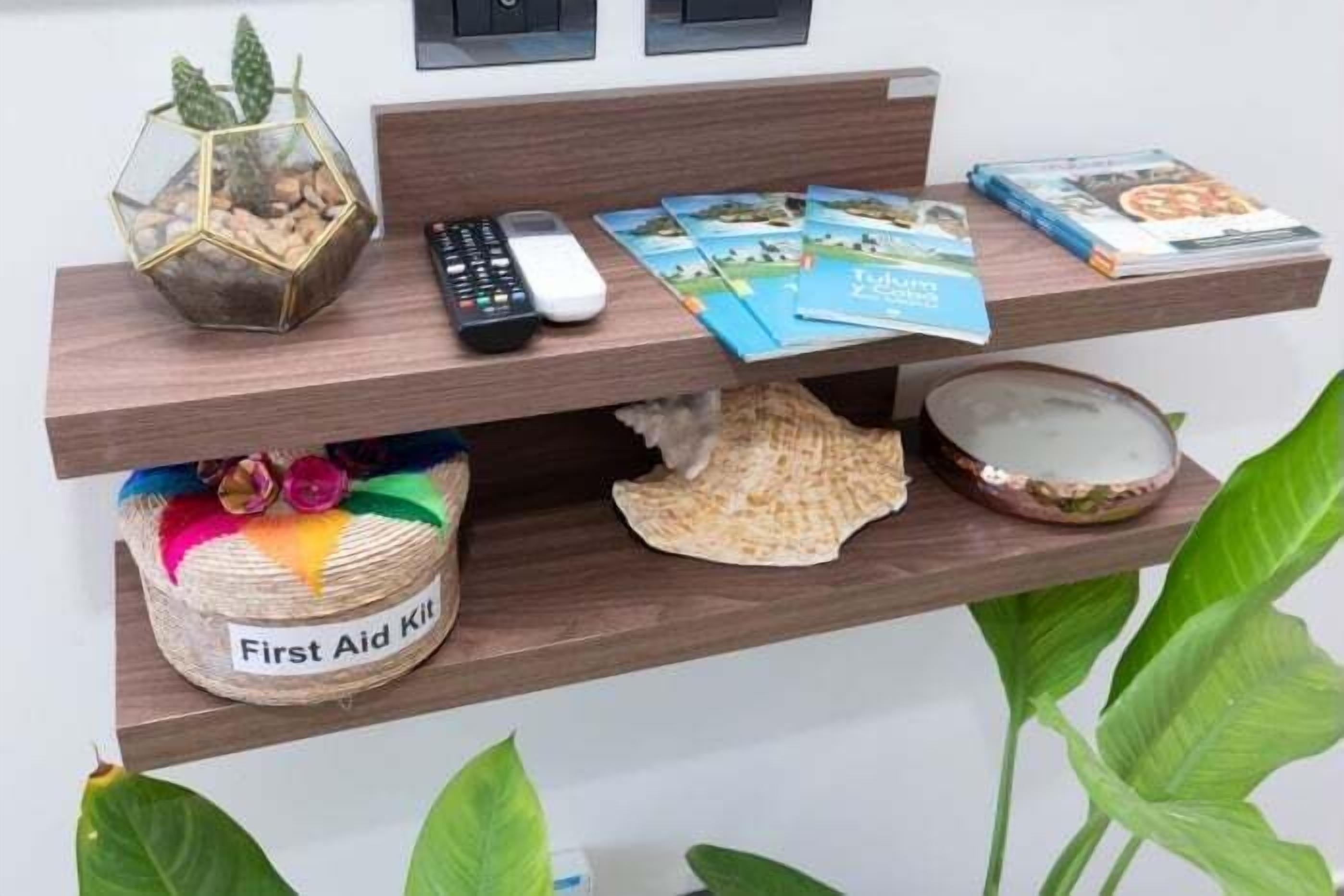 A wooden shelf with a remote control, books, a First Aid Kit, and decorative items.