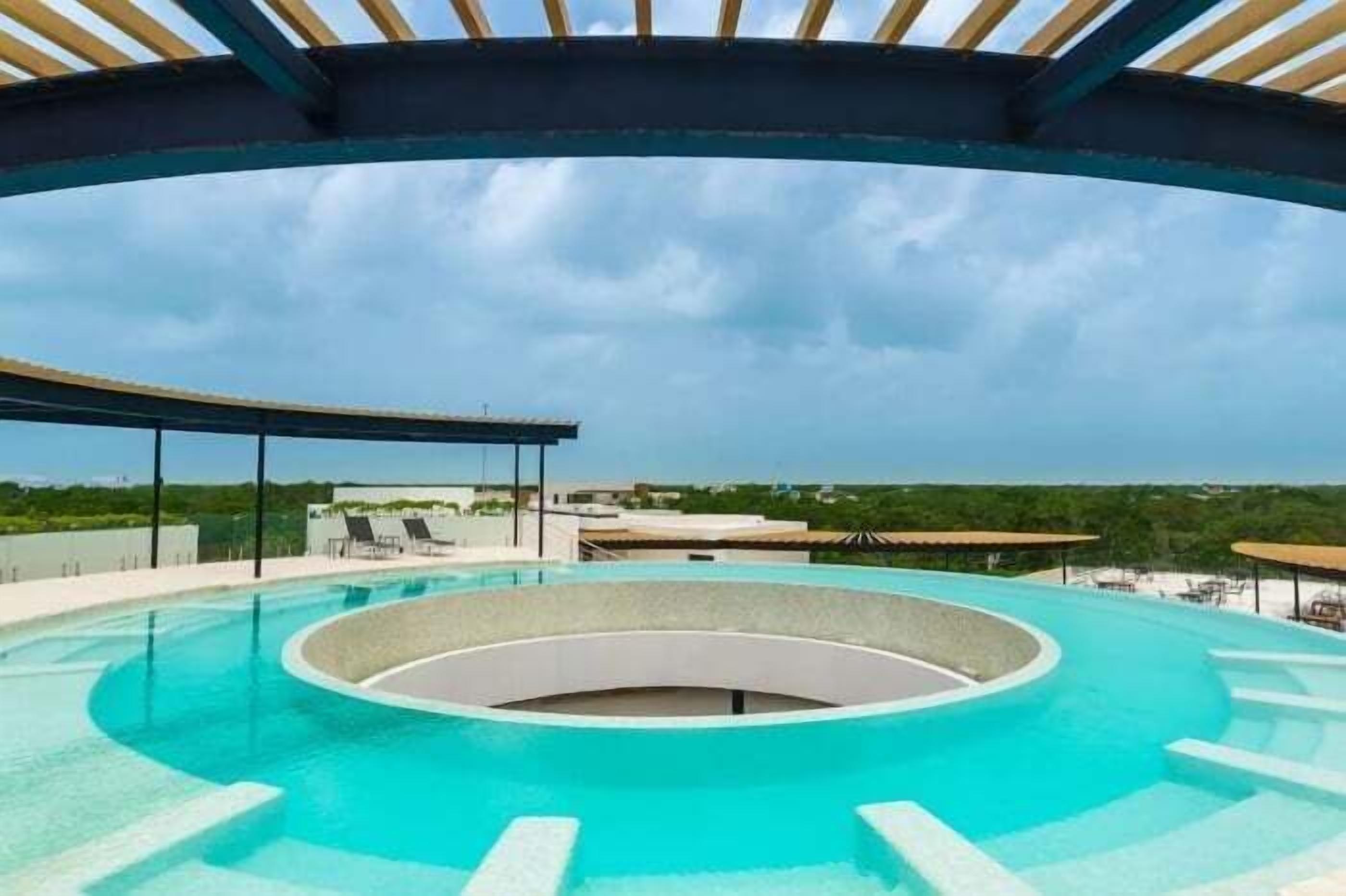 A circular infinity pool with a clear blue sky in the background.