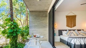 A modern bedroom with a large bed, bedside tables, and a hanging macrame wall decoration. - 101D PANOR, 360° infinity pool (Tulum)