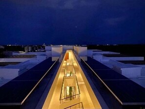 A rooftop terrace with a central walkway, surrounded by white structures, under a night sky. - 205D PANOR, Luxury Estudio Alberca 360° (Tulum)